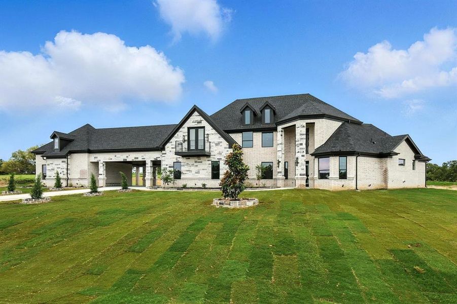 Back of house featuring a lawn, brick siding, and stone siding
