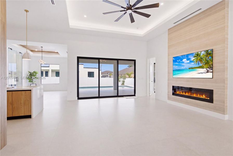 Spectacular great room features linear electric fireplace w/ floor-to-ceiling feature wall, creating the perfect gathering space while oversized sliding doors seamlessly blend indoor & outdoor living. Spectacular great room features linear electric fireplace w/ floor-to-ceiling feature wall, creating the perfect gathering space while oversized sliding doors seamlessly blend indoor & outdoor living.