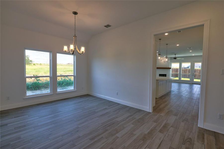 Unfurnished room with wood finished floors, a chandelier, a ceiling fan, a fireplace, and recessed lighting Unfurnished room with wood finished floors, a chandelier, a ceiling fan, a fireplace, and recessed lighting