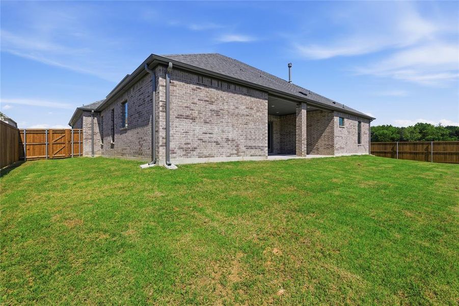 Expansive backyard featuring a manicured lawn, full privacy fencing, and a covered patio area