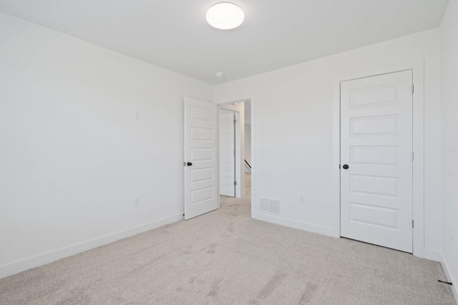 Light gray carpeting, white painted walls, white trim, recessed lighting, and panel interior doors