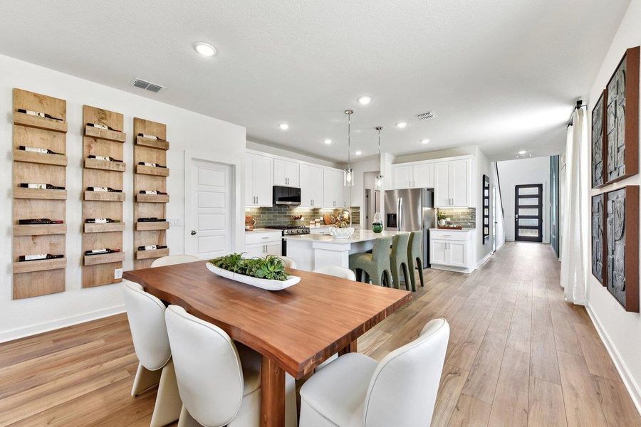 An open dining area flows seamlessly into a contemporary kitchen accented by wood flooring. An open dining area flows seamlessly into a contemporary kitchen accented by wood flooring.