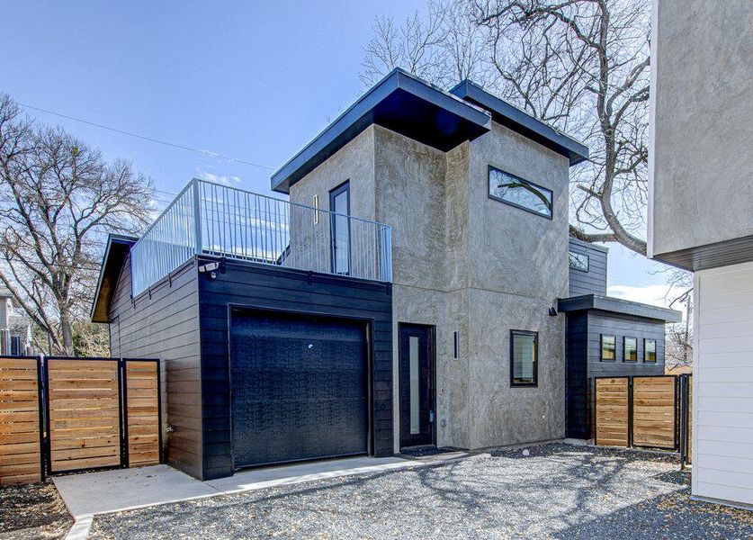 View of front facade with a gate, a balcony, and stucco siding