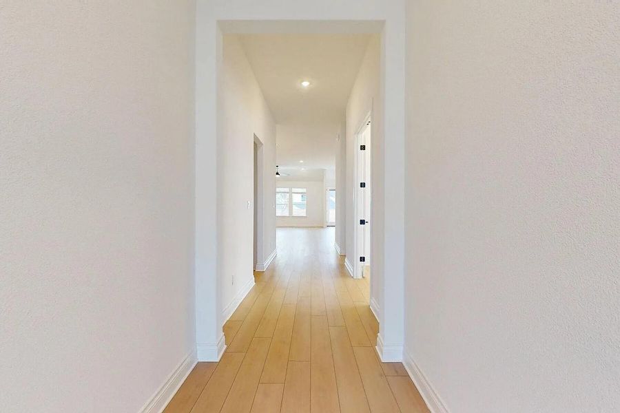 The property features a hallway with light-toned hardwood flooring and recessed lighting