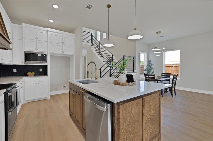Kitchen featuring appliances with stainless steel finishes, a sink, light wood-style flooring, white cabinets, and recessed lighting Kitchen featuring appliances with stainless steel finishes, a sink, light wood-style flooring, white cabinets, and recessed lighting