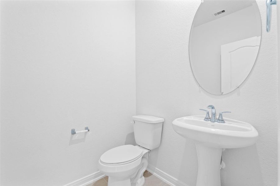 Perfectly situated on the main level for guests and residents, this charming powder room features a pedestal sink, mirror, and toilet.