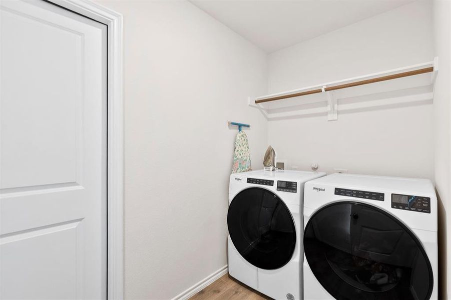 Laundry room with light wood-type flooring and washer and clothes dryer Laundry room with light wood-type flooring and washer and clothes dryer