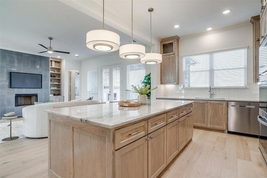 Kitchen featuring Quartzite countertops, tasteful backsplash, light hardwood / wood-style flooring, a kitchen island, and appliances with stainless steel finishes