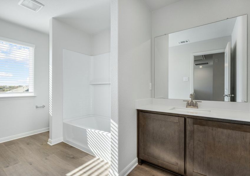 The secondary bathroom has a sprawling vanity and a shower-tub combo.