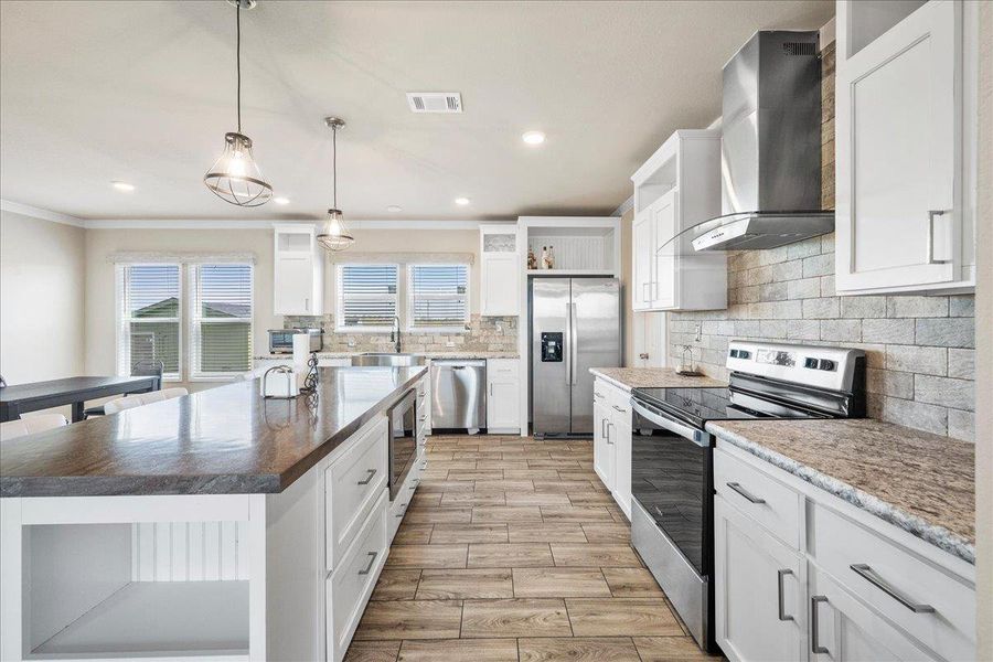 Kitchen with stainless steel appliances, open shelves, white cabinetry, a kitchen island, and wood tiled floors Kitchen with stainless steel appliances, open shelves, white cabinetry, a kitchen island, and wood tiled floors