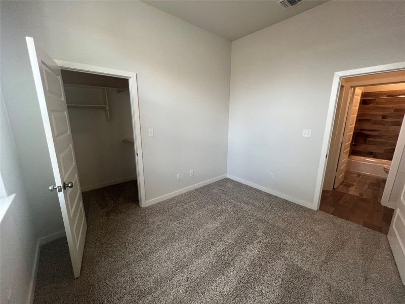 A well-proportioned room with plush carpeting offers convenient access to a spacious closet and a nearby bathroom.