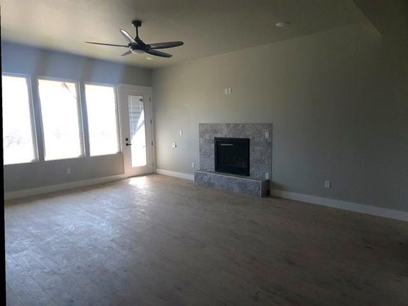 Unfurnished living room featuring ceiling fan, wood finished floors, and a premium fireplace