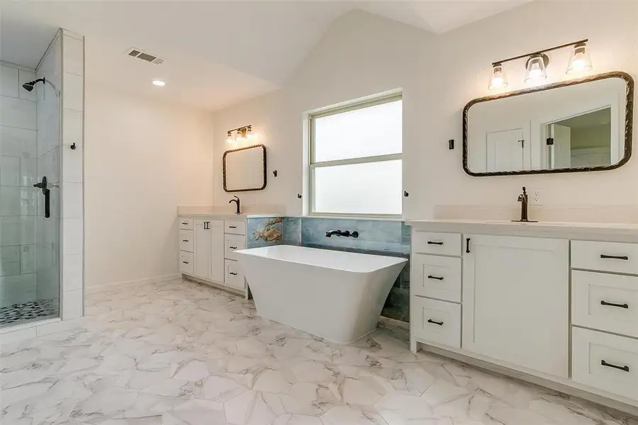 Bathroom with lofted ceiling, dual vanities, a tile shower, and tile floors Bathroom with lofted ceiling, dual vanities, a tile shower, and tile floors