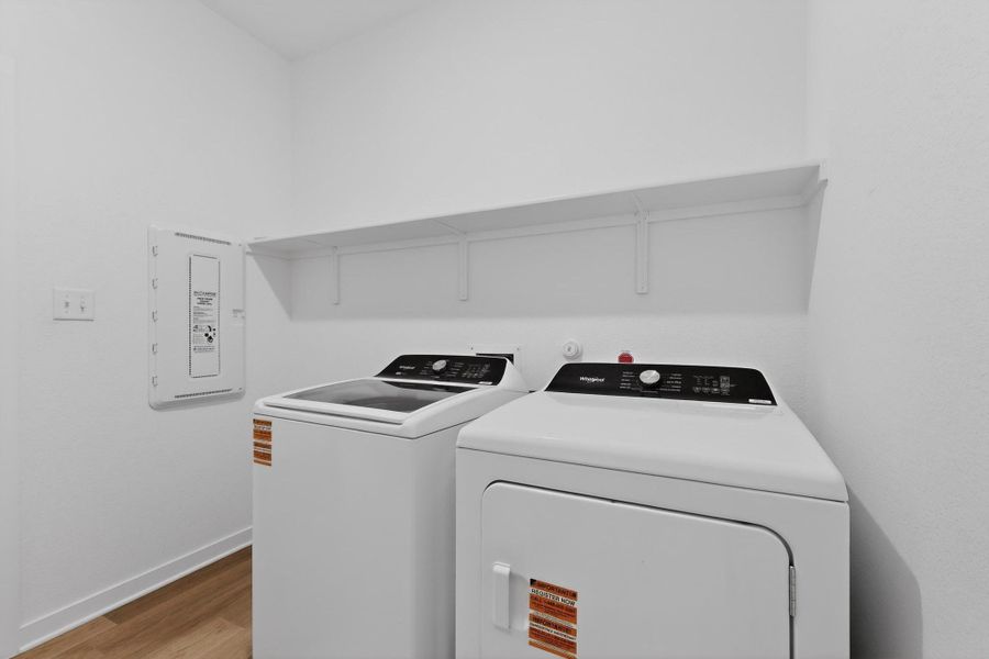 Laundry room with light wood-style floors, washing machine and clothes dryer, and electric panel