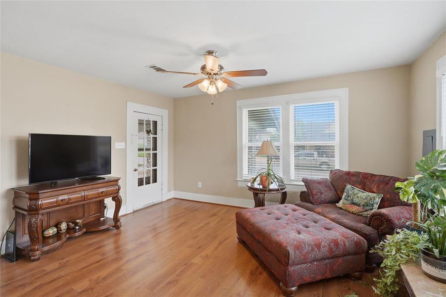 Living area featuring wood-finish flooring, neutral wall tones, and a ceiling fan with light fixture