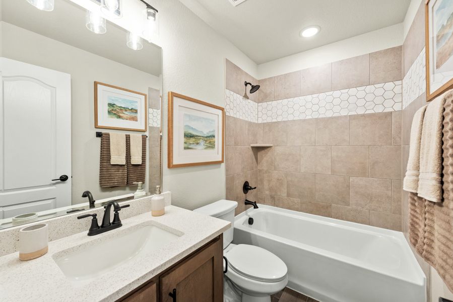 Bathroom with quartz vanity, tub-shower combo, and beige tile surround with hexagon accent strip
