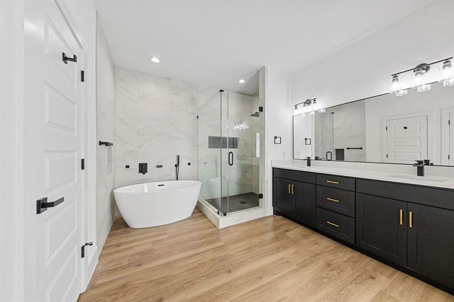 This bathroom features light wood-style flooring, a freestanding bathtub with dark fixtures, and a glass-enclosed shower This bathroom features light wood-style flooring, a freestanding bathtub with dark fixtures, and a glass-enclosed shower