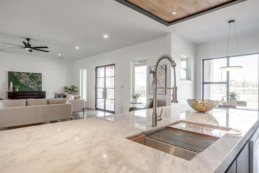 Kitchen featuring open floor plan, light stone counters, a sink, and recessed lighting