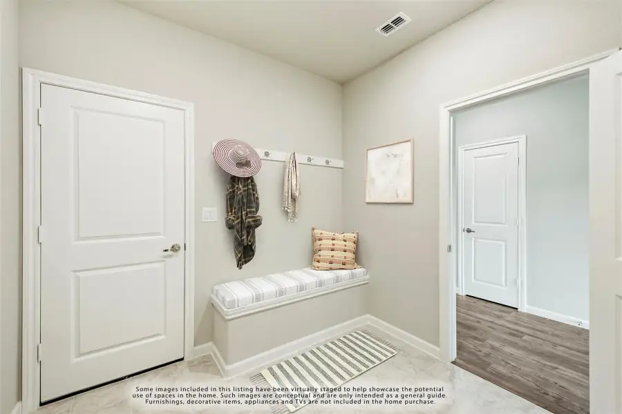 Mudroom entryway with built-in bench, wall coat hooks, and striped area rug on tile floor