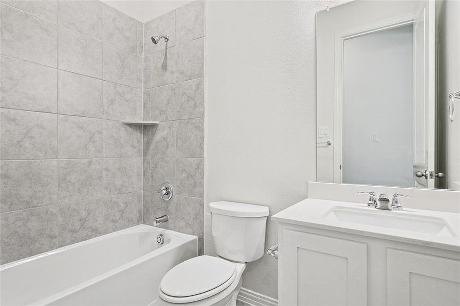 Full bathroom featuring vanity, tiled shower / bath combo, and toilet