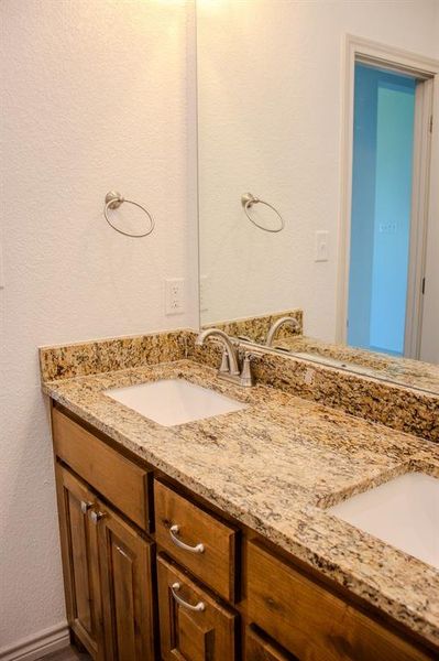 Bathroom featuring a textured wall and double vanity Bathroom featuring a textured wall and double vanity