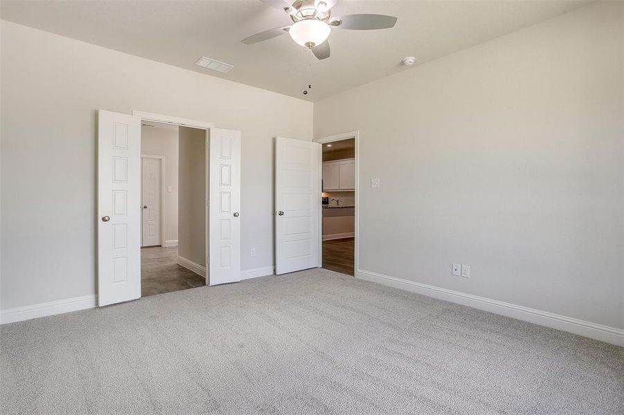 Unfurnished bedroom with light colored carpet and a ceiling fan