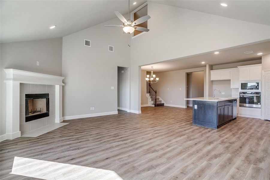 wood-style flooring, ceiling fan with notable chandelier, and high vaulted ceiling wood-style flooring, ceiling fan with notable chandelier, and high vaulted ceiling