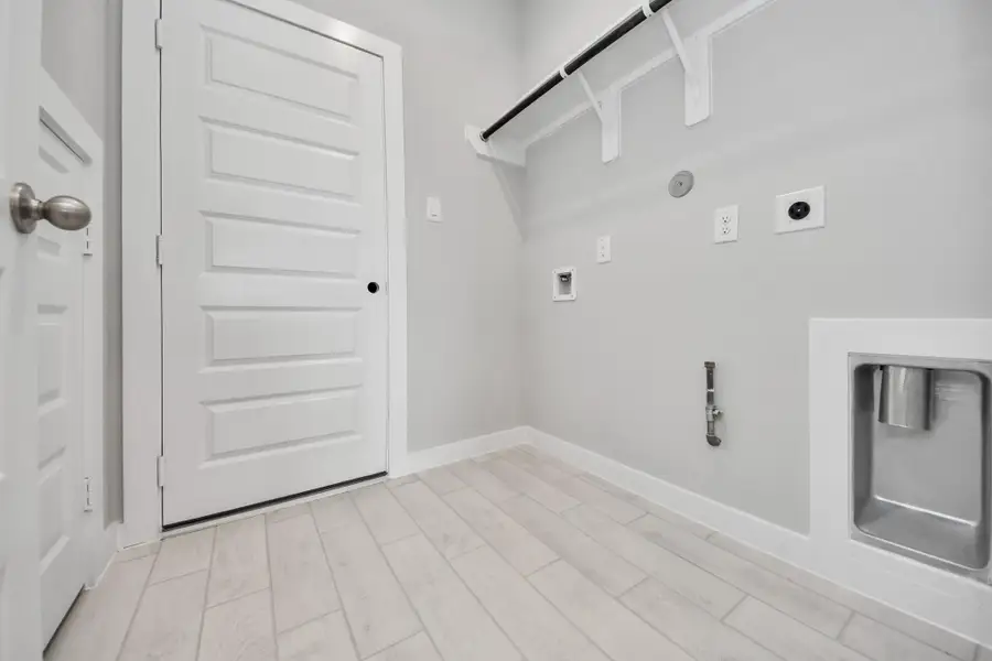 A perfect blend of functionality and comfort. Capture the essence of easy living with a first-floor laundry room, thoughtfully equipped with shelving for effortless organization. Both electric and gas connections available. Sample photo of completed home with similar floor plan. Actual colors and selections may vary.