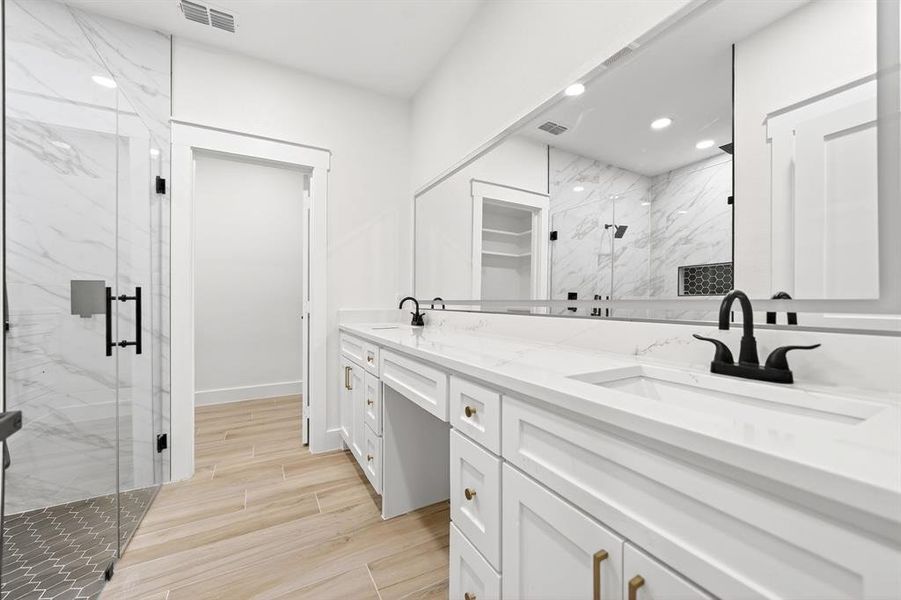 Bathroom featuring a double vanity with white cabinetry, gold-toned hardware, and white countertops Bathroom featuring a double vanity with white cabinetry, gold-toned hardware, and white countertops