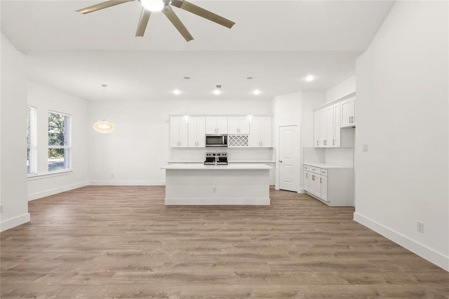 Unfurnished living room with ceiling fan and light hardwood / wood-style flooring