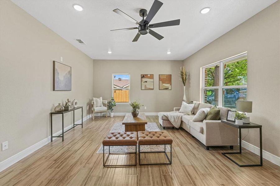 Living room featuring plenty of natural light, recessed lighting, light wood-type flooring, and ceiling fan Living room featuring plenty of natural light, recessed lighting, light wood-type flooring, and ceiling fan