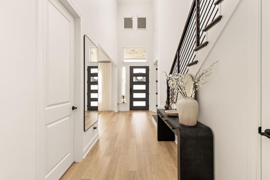 Two-story foyer featuring wood-finish flooring, a modern black iron staircase, and a double-door entry with frosted glass panels