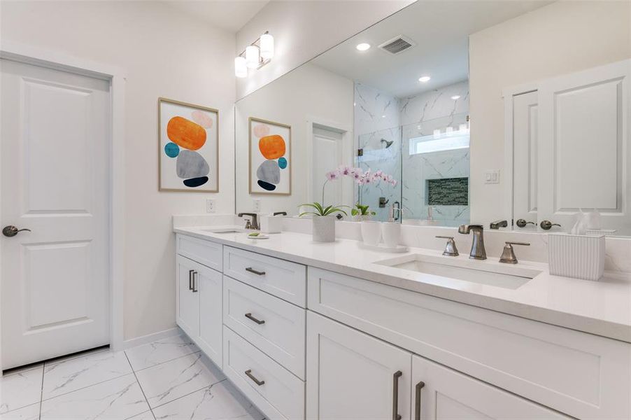 Bathroom with light marble finish flooring, a marble finish shower, and double vanity