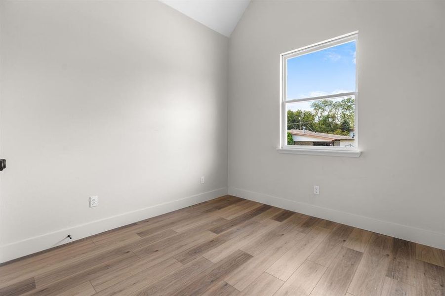 Empty room featuring wood finished floors and vaulted ceiling