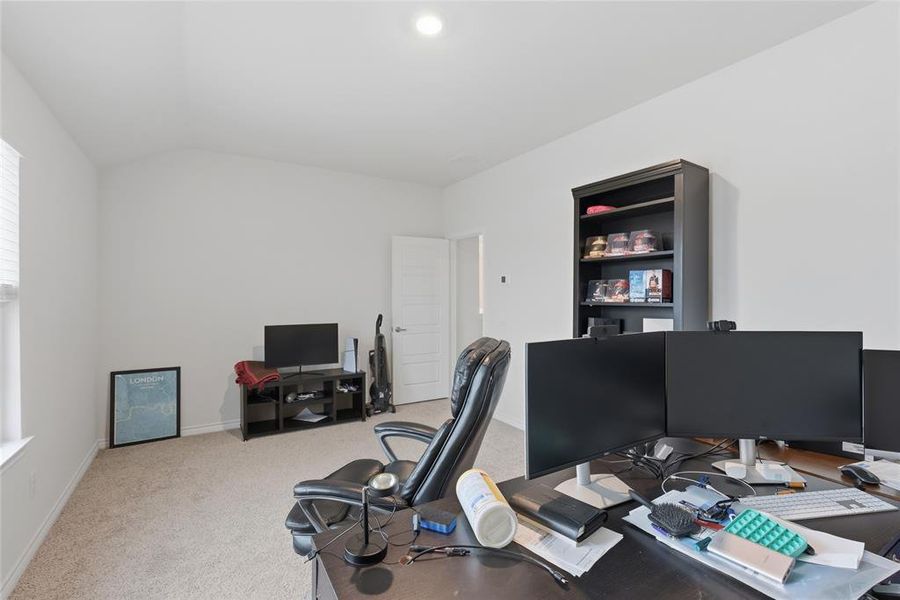 Spacious interior room featuring a vaulted ceiling, recessed lighting, and neutral carpeting
