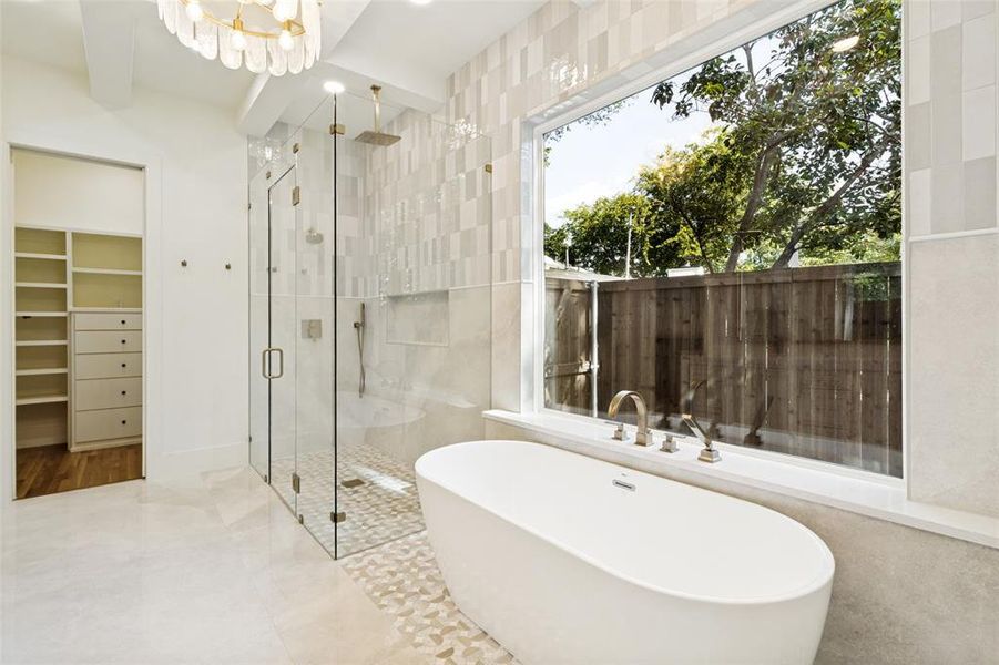 Freestanding soaking tub with brushed brass fixtures, complemented by a large picture window Freestanding soaking tub with brushed brass fixtures, complemented by a large picture window