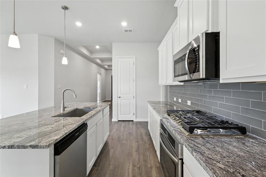 Kitchen with stainless steel appliances, dark wood finished floors, white cabinetry, decorative backsplash, and recessed lighting