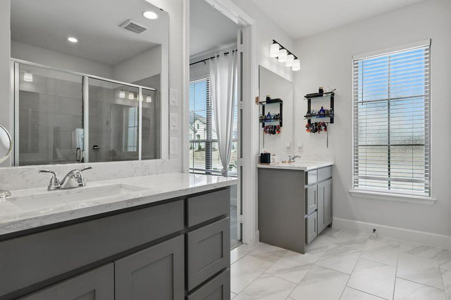 Full bathroom featuring a stall shower, two vanities, visible vents, and a sink