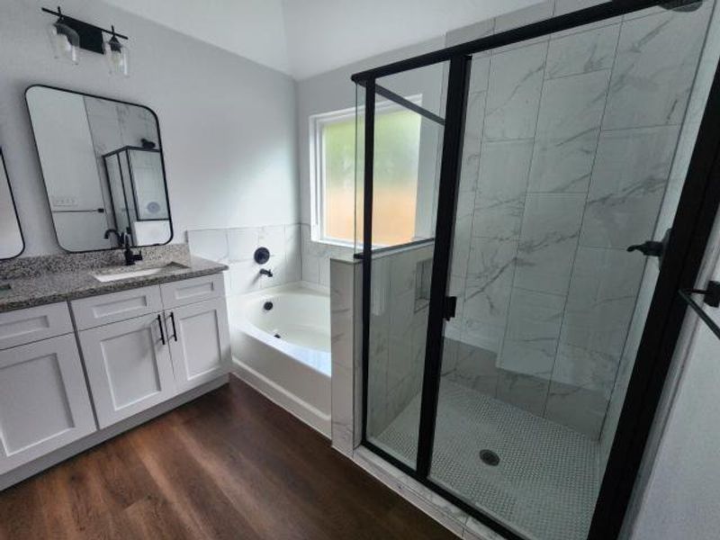Full bath with a garden tub, a marble finish shower, dark wood-style flooring, and vanity Full bath with a garden tub, a marble finish shower, dark wood-style flooring, and vanity