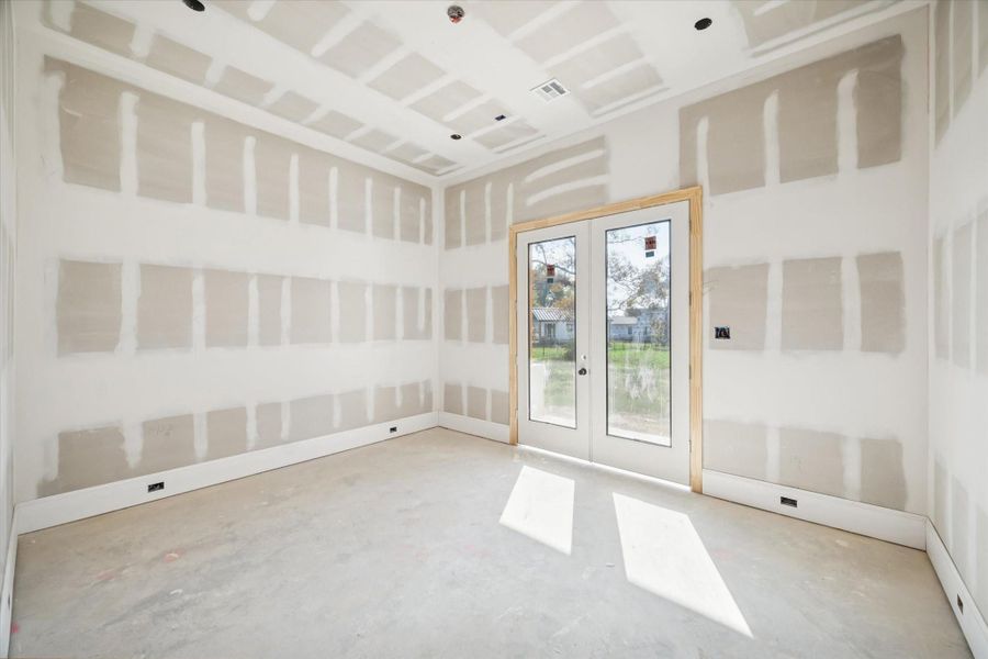 This secondary bedroom features great natural light and direct access to the outdoor porch, giving the space a unique indoor-outdoor connection. The clean drywall finish and framing set the stage for trim, paint, and flooring. A comfortable retreat ideal for guests or extended family.