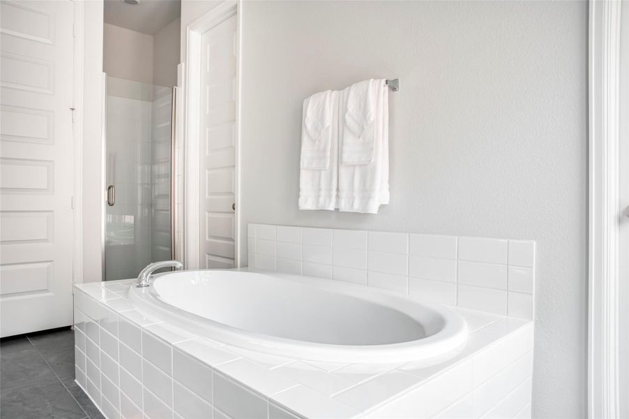 This bathroom features a modern, bright design with a sleek white bathtub, tiled surround, glass-enclosed shower, and soft gray walls, creating a relaxing and inviting atmosphere. This bathroom features a modern, bright design with a sleek white bathtub, tiled surround, glass-enclosed shower, and soft gray walls, creating a relaxing and inviting atmosphere.