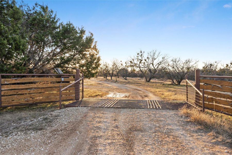 View of dirt / gravel road with a gate and a rural view