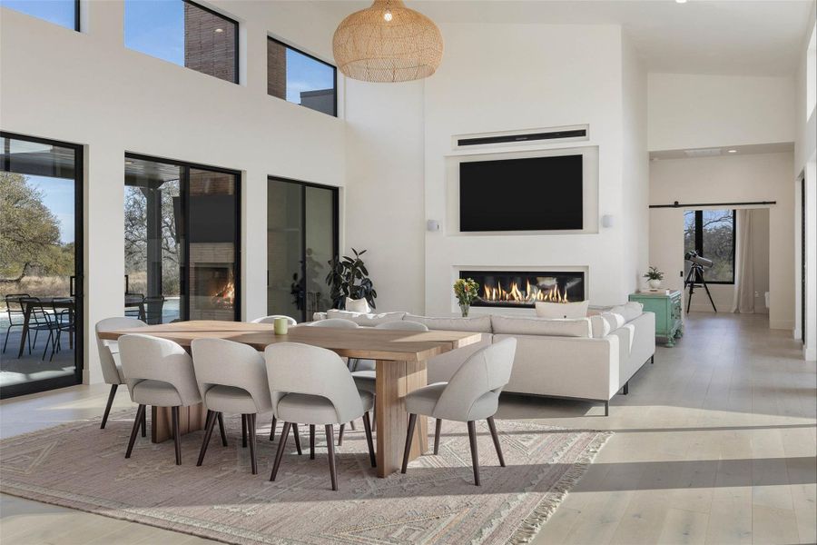 Dining area with a glass covered fireplace, a high ceiling, and light wood-type flooring