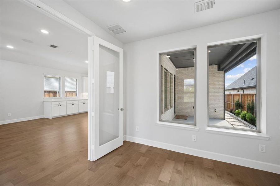 Private office or flex space with hardwood  flooring, recessed lighting, glass French doors, and multiple windows flooding the room with natural light.