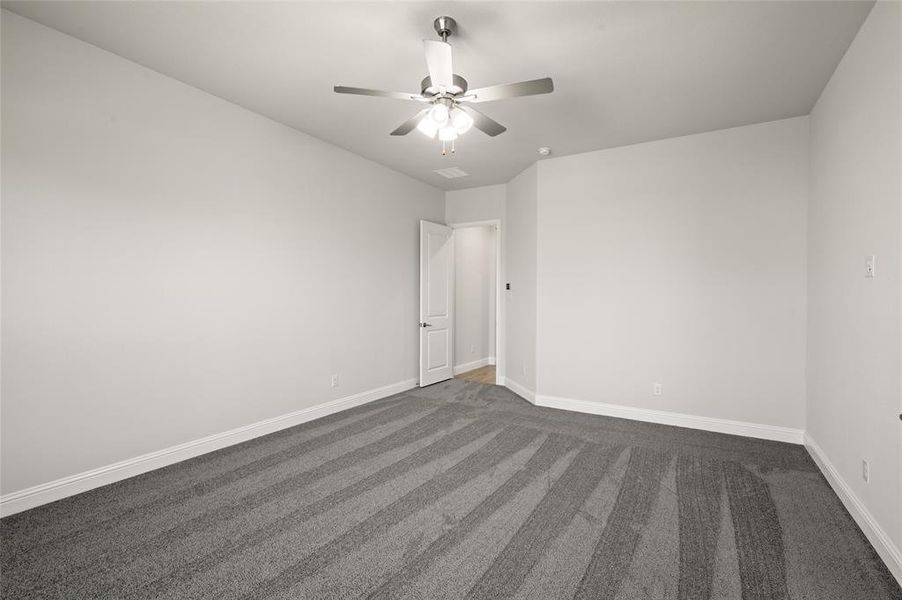Empty room featuring baseboards, dark colored carpet, and a ceiling fan Empty room featuring baseboards, dark colored carpet, and a ceiling fan