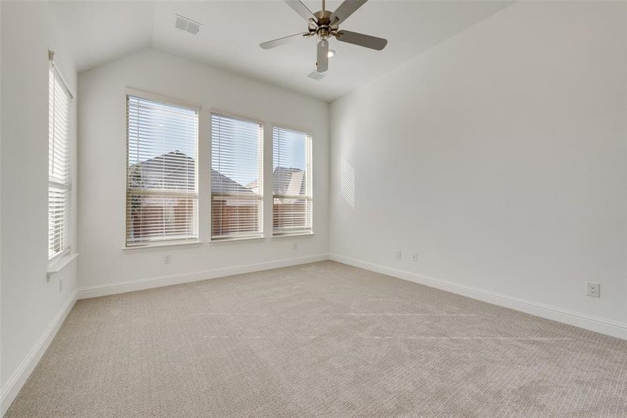 Carpeted spare room featuring ceiling fan and lofted ceiling