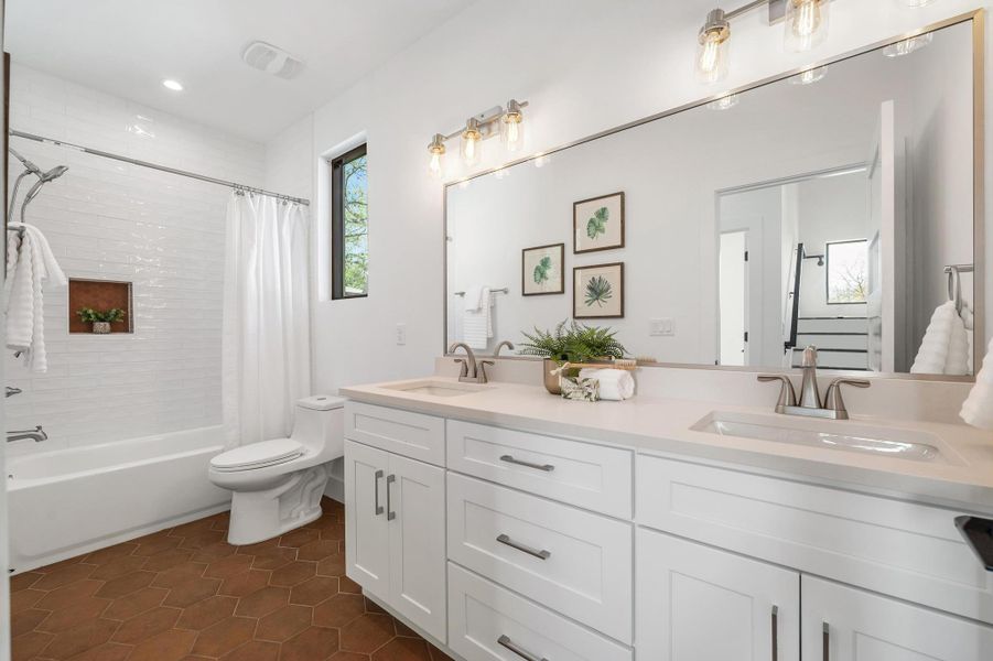 Bathroom featuring tile patterned flooring, double vanity, shower / bathtub combination with curtain, and a sink