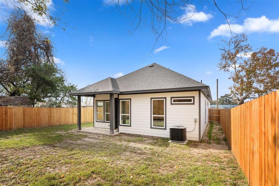 Rear view of house featuring roof with shingles, a patio, and a fenced backyard