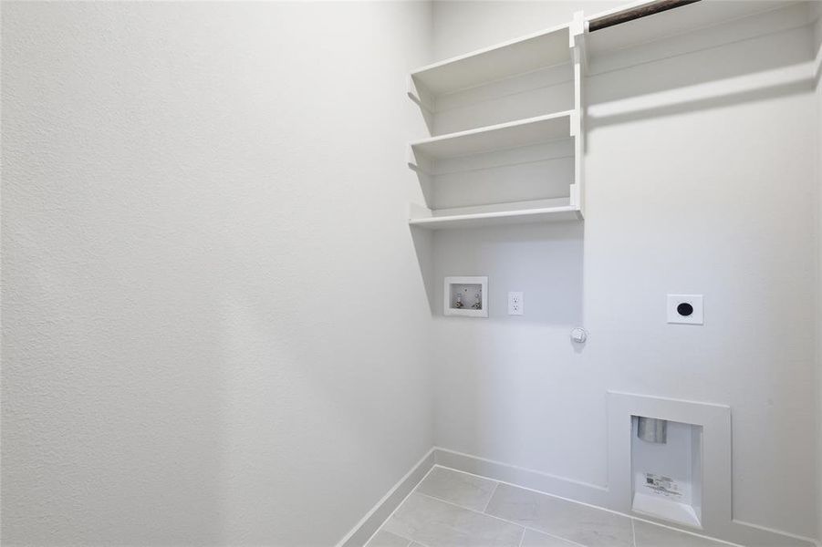 Utility space featuring integrated shelving, a clothes hanging rod, tiled flooring, and appliance hookups