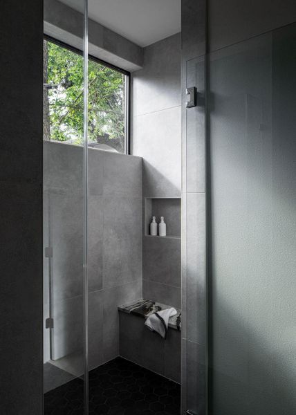 Serenity awaits in the guest shower with walls of warm tile and a beautiful marble bencn.